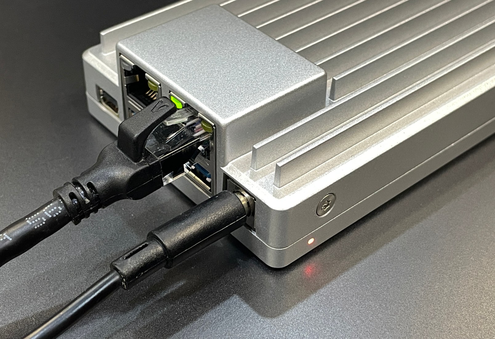 Parte trasera de ZimaBoard 2 con Ethernet 2.5GbE y alimentación 12V conectados, LED de encendido activo—configuración inicial de mini NAS.